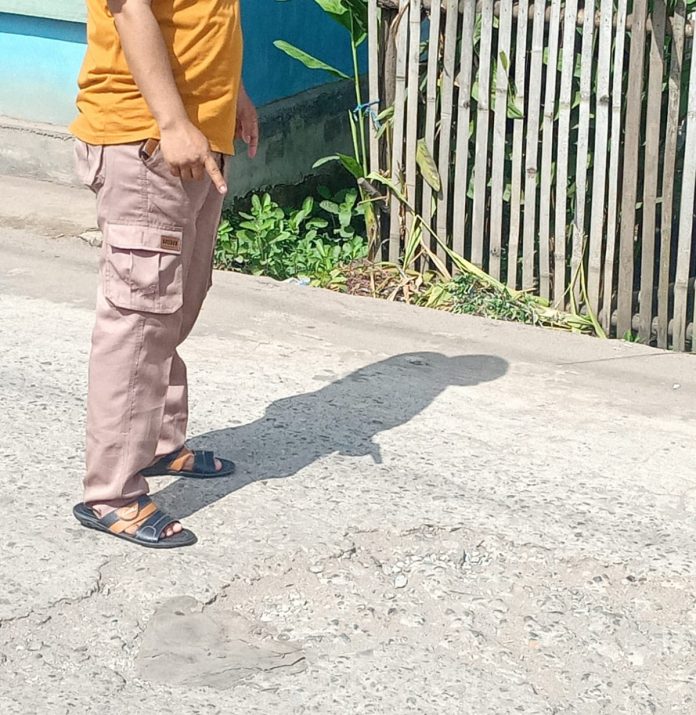 Salah satu warga menunjukkan jalan yang rusak (dok.istimewa)