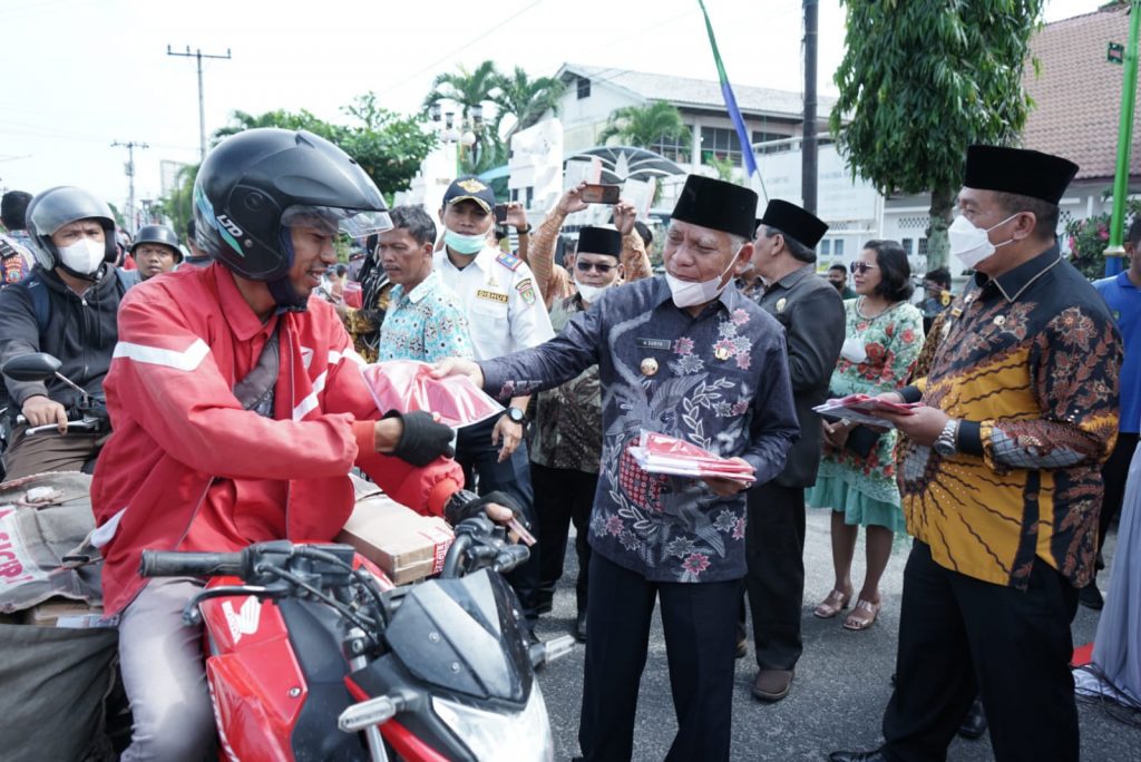 Keteranga foto : Bupati didampingi Wakil Bupati Asahan secara simbolis membagikan Bendera Merah Putih kepada masyarakat Kabupaten Adahan.(dok/istimewa)