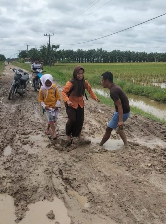 Anak anak sekolah kesulitan saat melintas di jalan yang rusak parah dan berlumpur. ( foto/Joko )